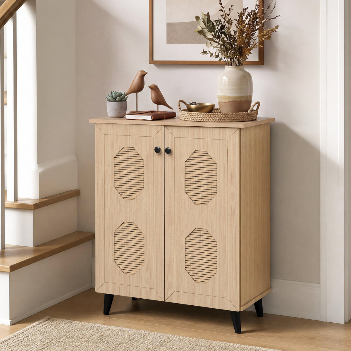 Natural-toned cabinet with geometric carved doors stands beside a staircase, styled with plants and decor.