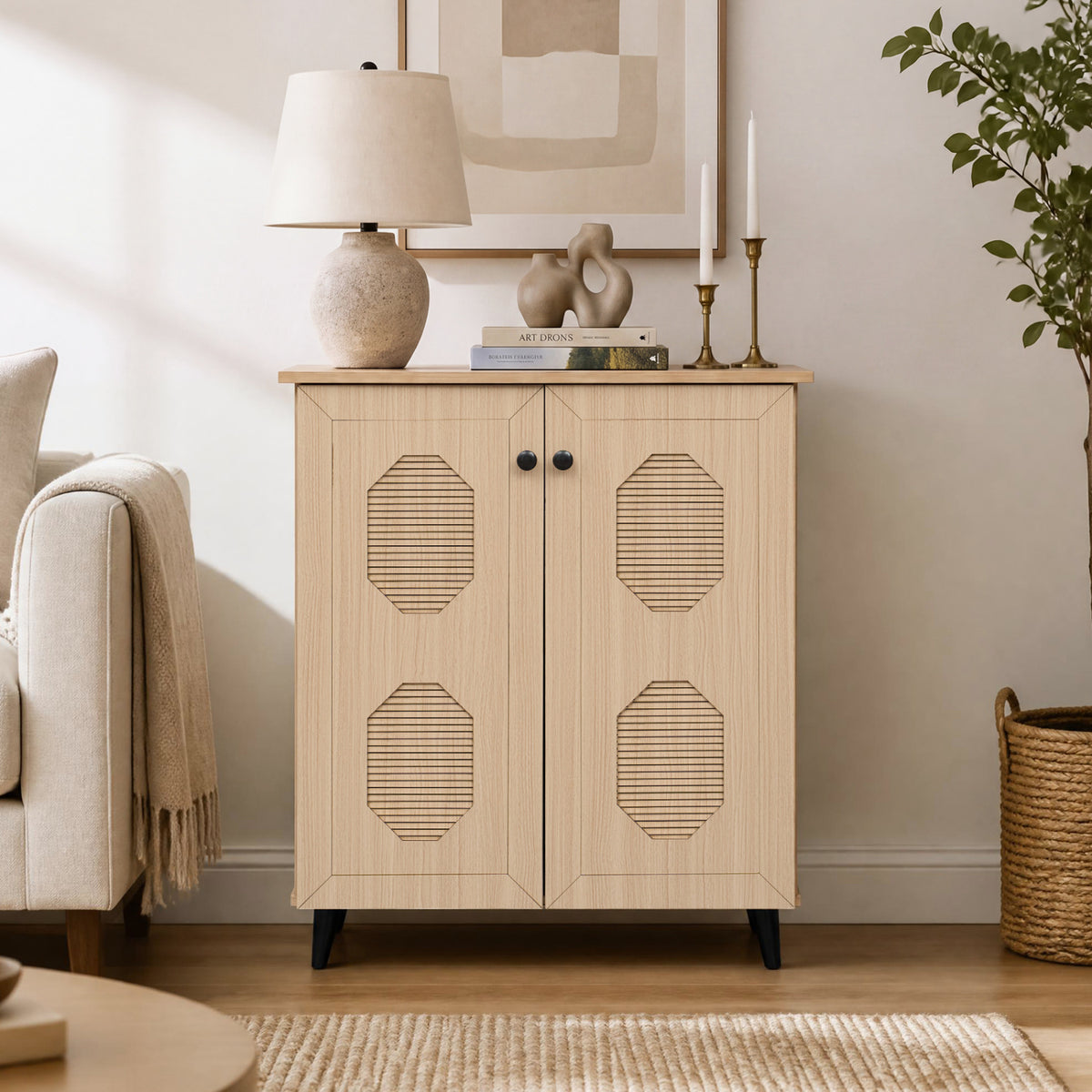Front view of the light wood cabinet in a living room, with a lamp and decor arranged on top.