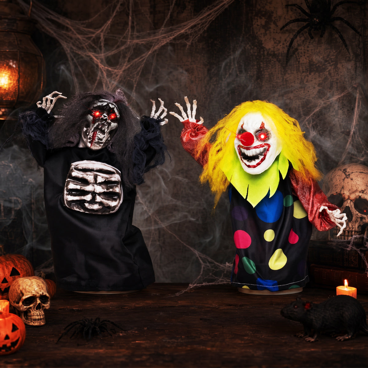 The reaper and clown raise their hands in a cobweb-filled Halloween scene with a skull and pumpkins.