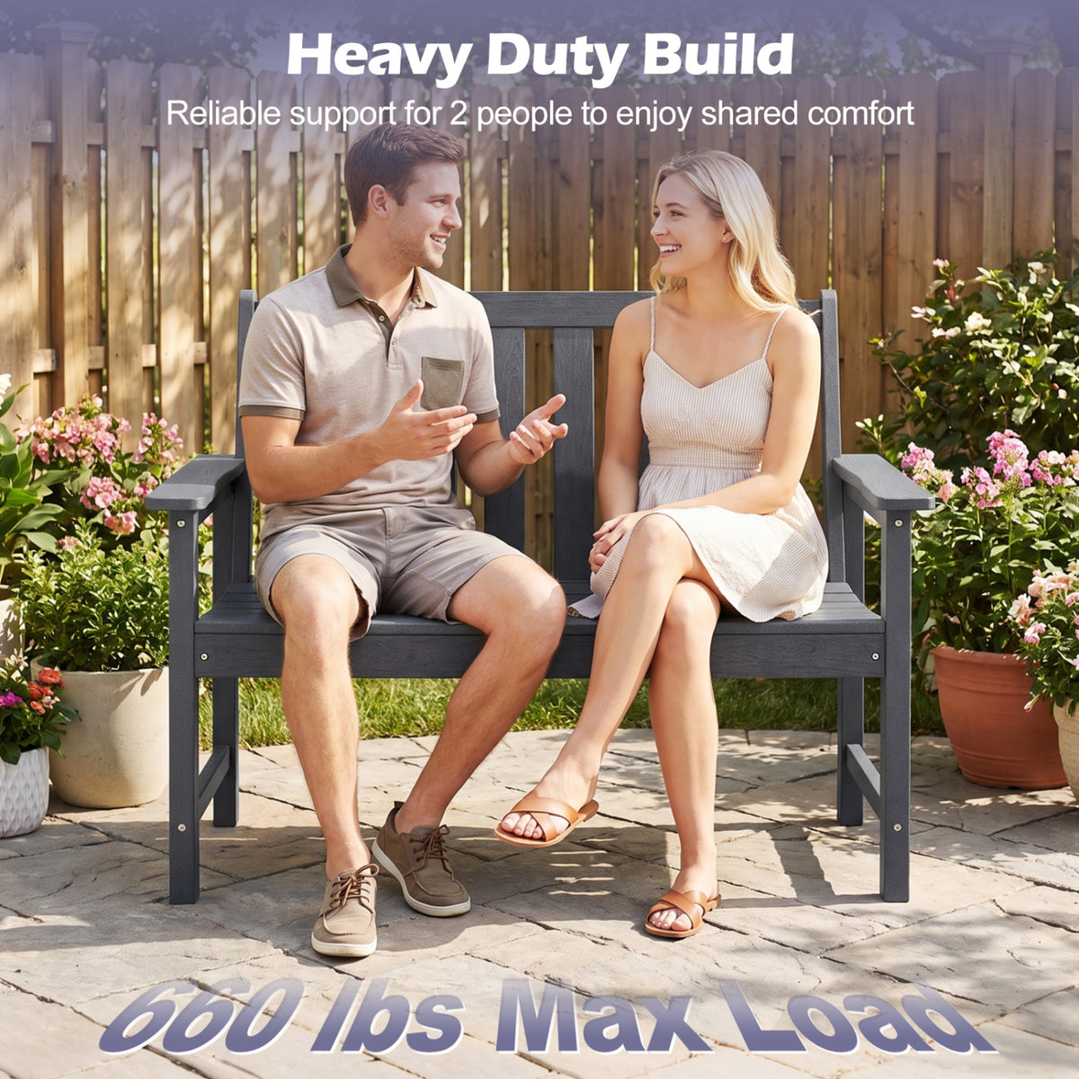 A man and woman sit together on a charcoal slatted bench in a garden.