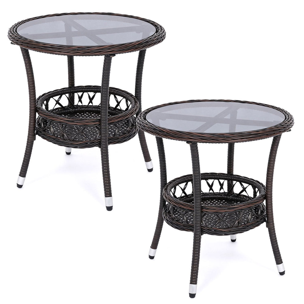 Two dark woven bistro tables with glass tops and lower shelves on white