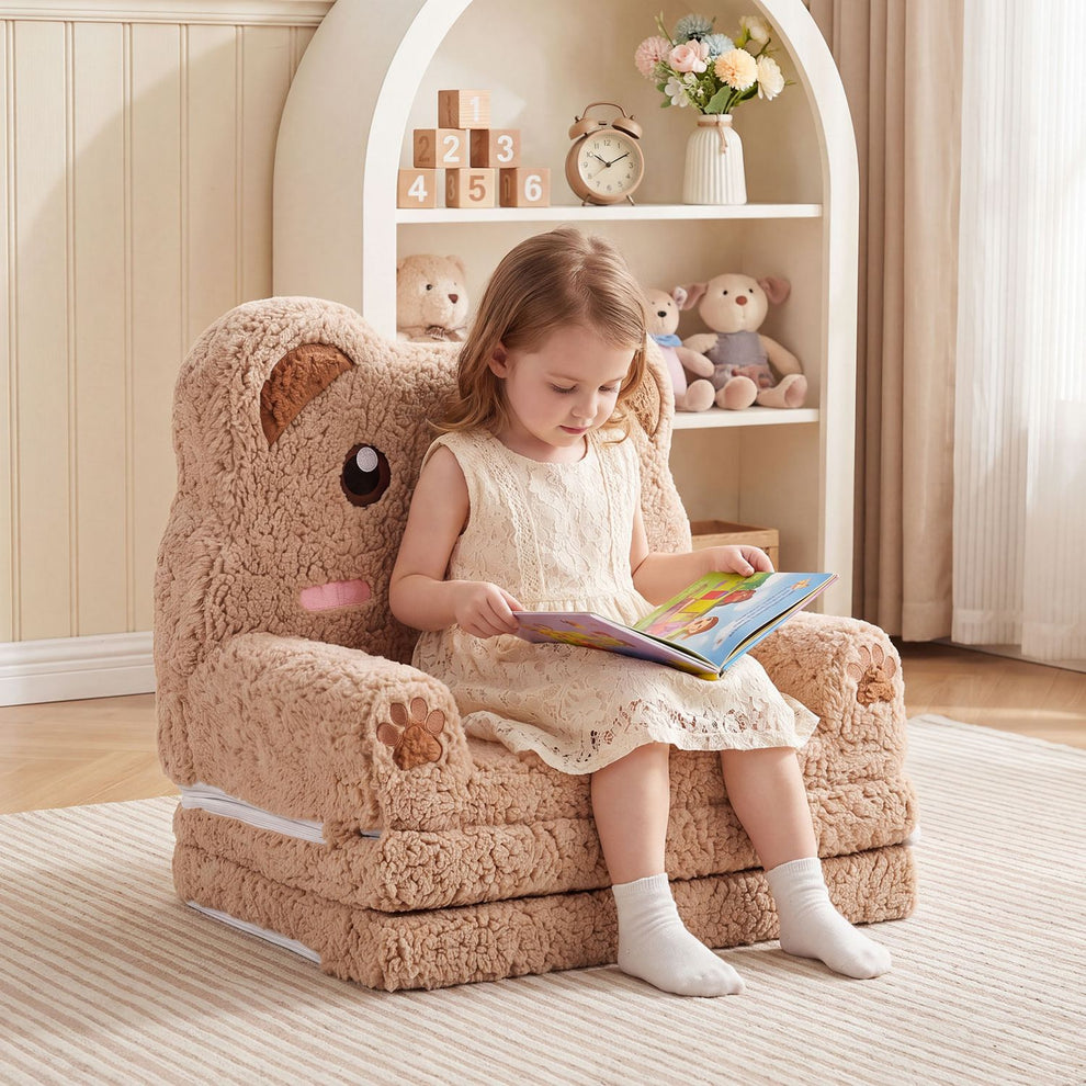 A child reads in a plush bear-shaped sofa with rounded arms and a tall character back.