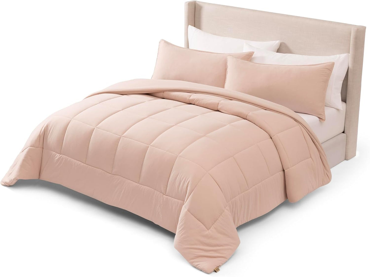Soft blush comforter draped over a full bed with two coordinating rectangular shams