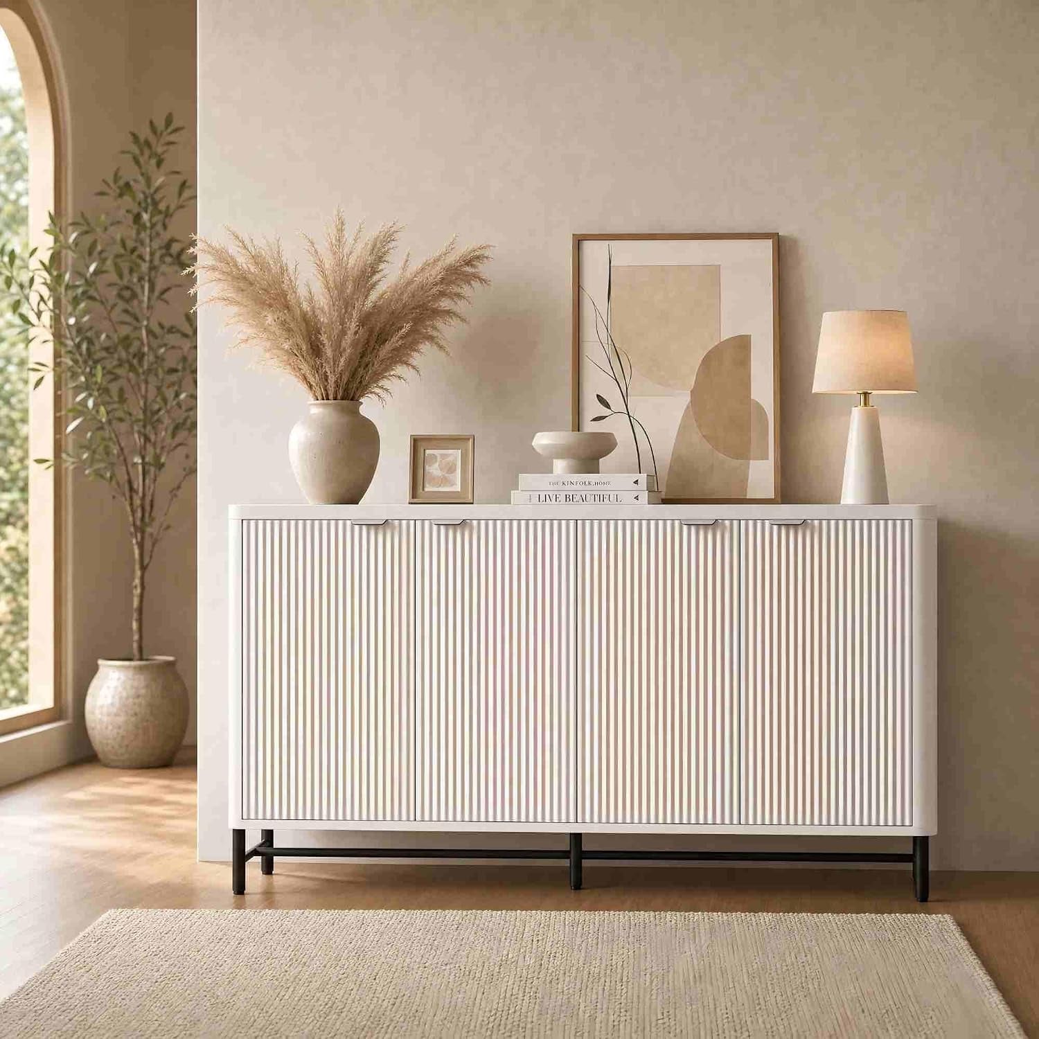 Front view of a low white sideboard with vertical fluted doors and black metal legs in a styled room.