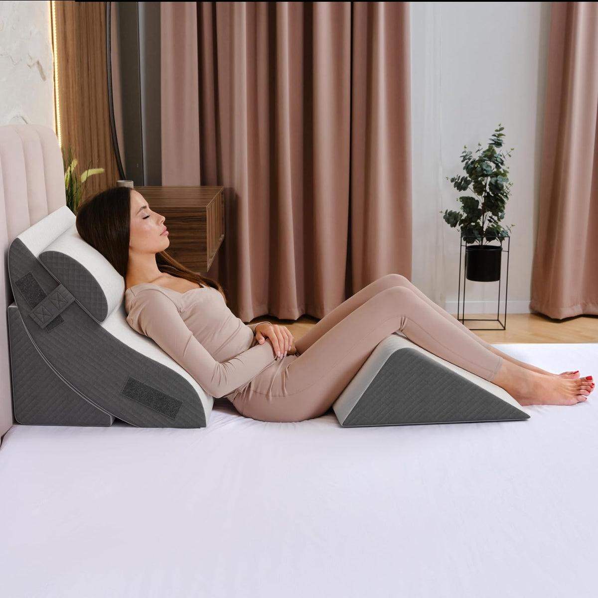 Side view of a woman reclined using a multi-piece wedge setup with a detachable cylindrical neck cushion attached by straps.