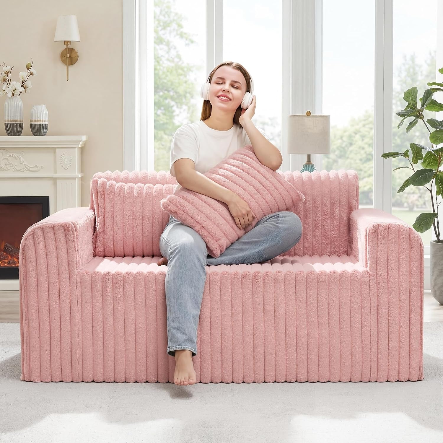Pink ribbed floor sofa shown in a living room with a woman seated smiling and holding a matching pillow.