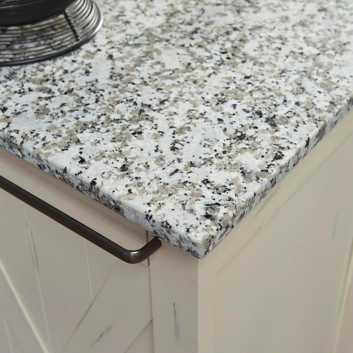 Close-up of salt-and-pepper granite countertop edge and dark metal towel bar on the cart corner