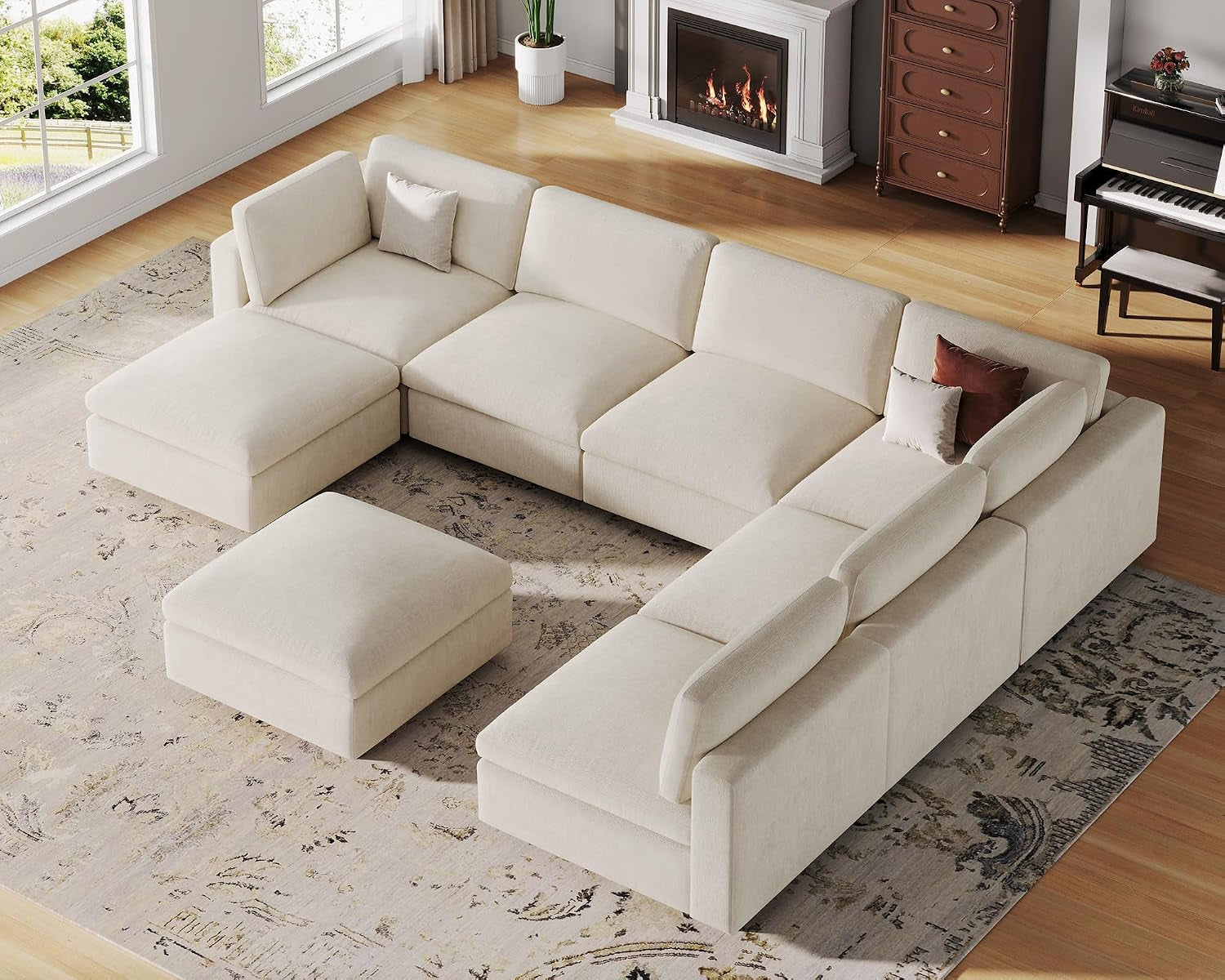 Angled overhead view of a light cream modular corner sectional with matching square ottoman on a patterned rug.