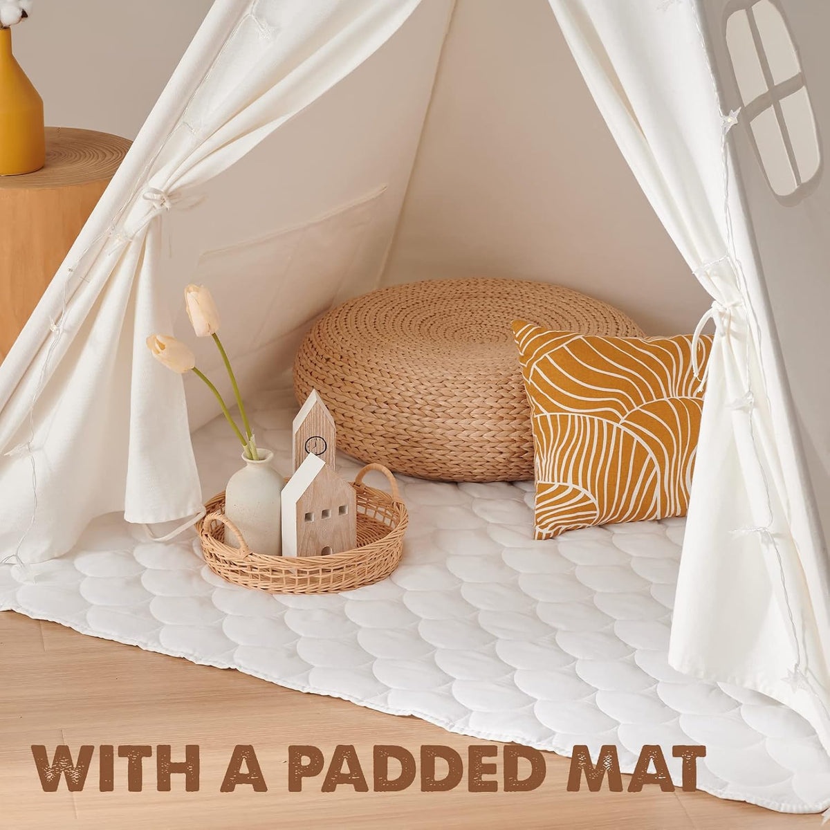 Interior close-up of the tent showing a quilted padded mat, a woven floor pouf and a patterned throw pillow.