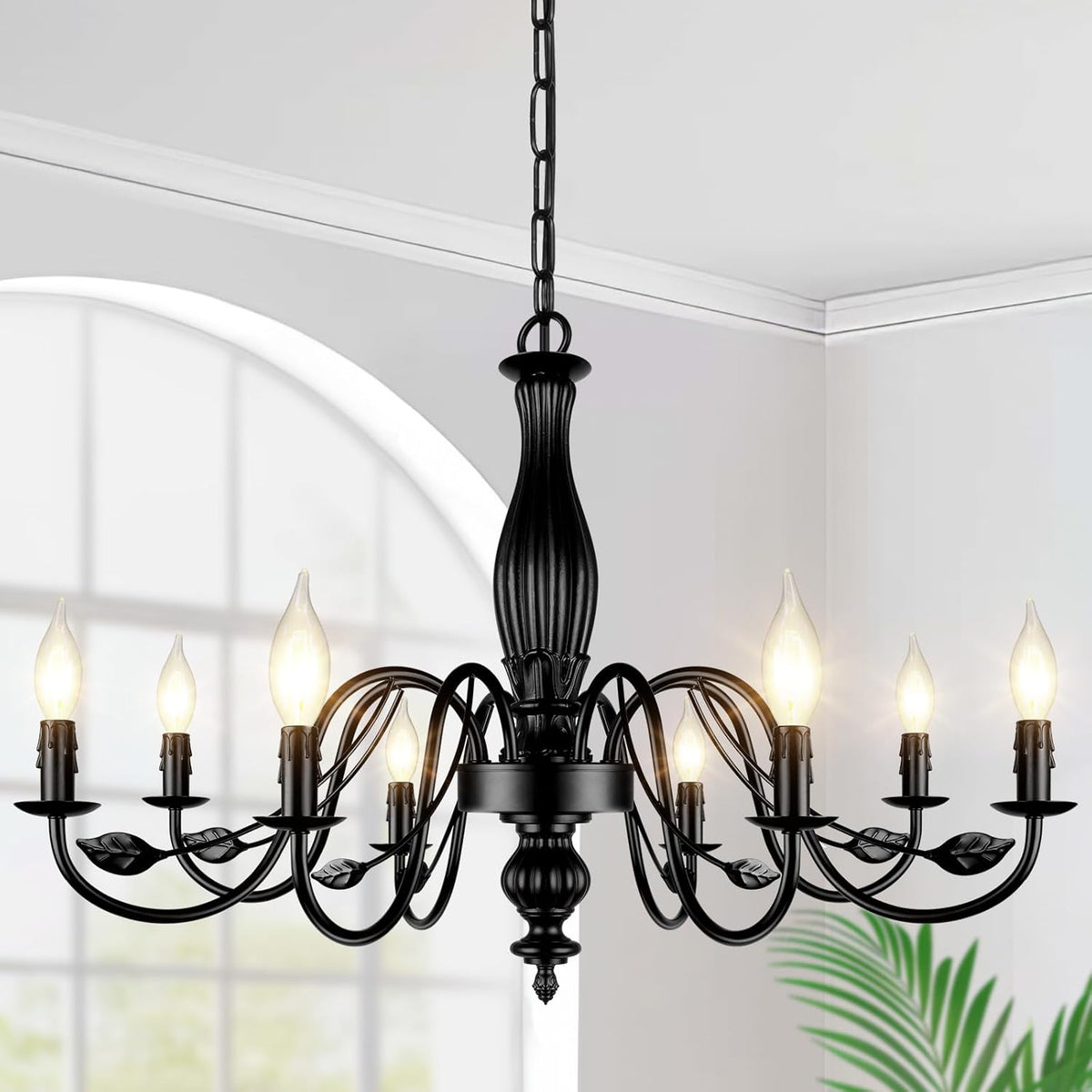 Matte black six-light chandelier with curved arms and leaf accents against a windowed wall