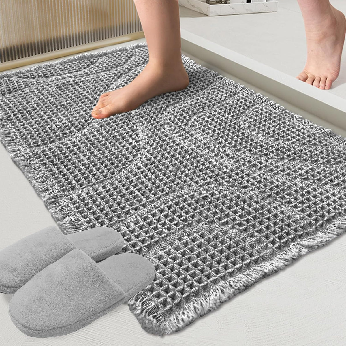 Close view of a gray wavy-textured mat with fringe as a bare foot steps onto it.