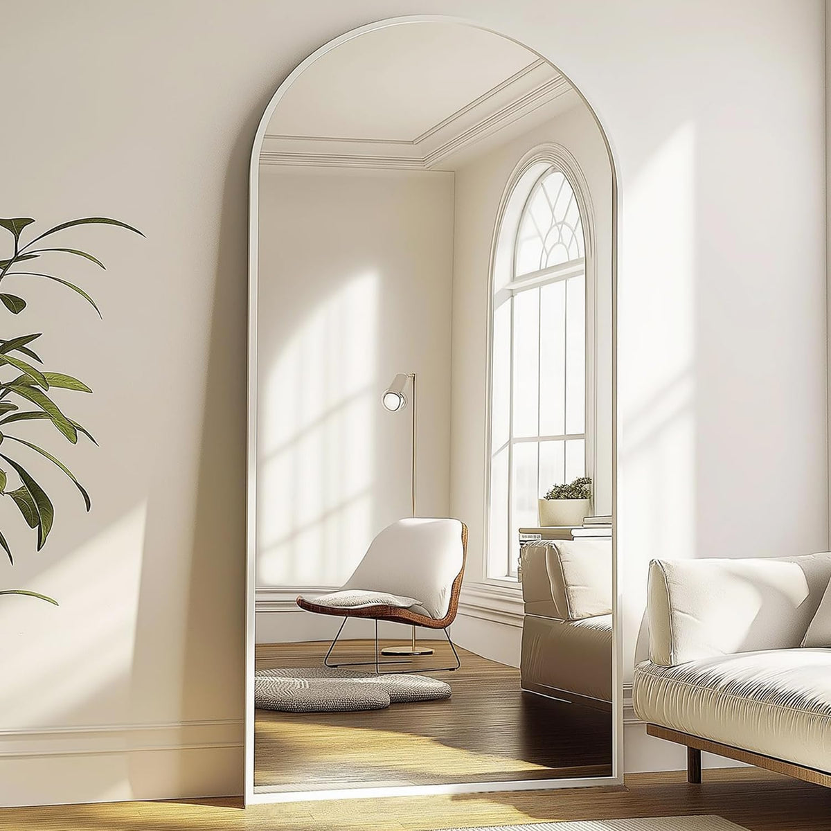 Close-up of the arched mirror top showing a pale frame and a window reflected in soft daylight.
