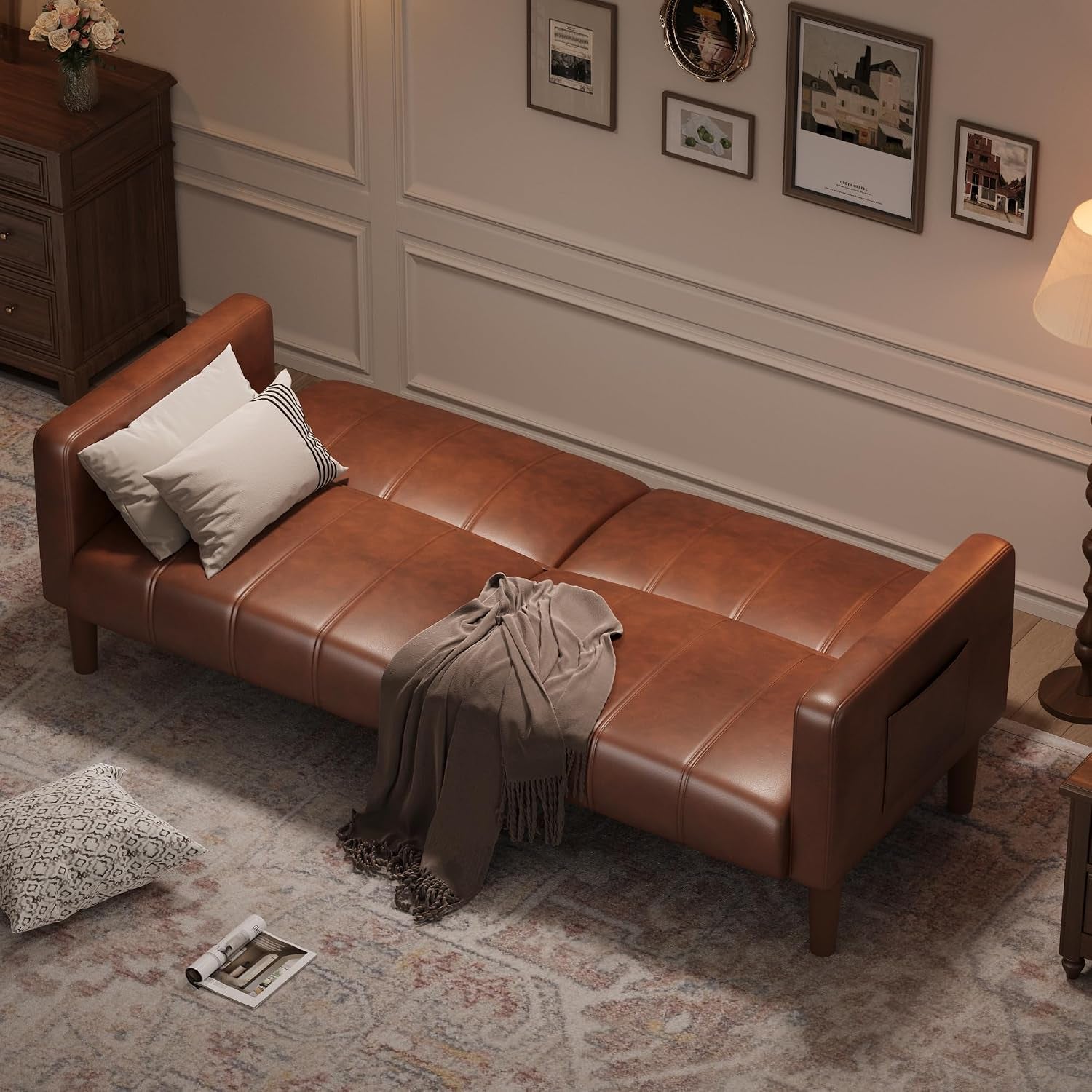 Brown faux leather futon laid flat as a twin-size sleeper with pillows and blanket