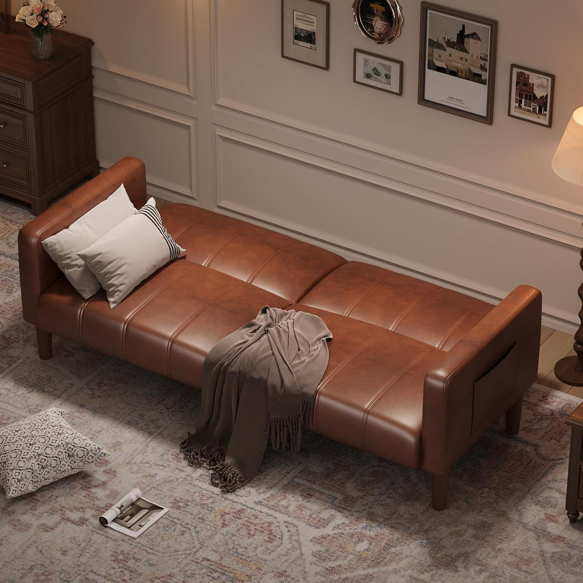 Brown faux-leather sofa bed set up flat as a daybed in a softly lit living room.