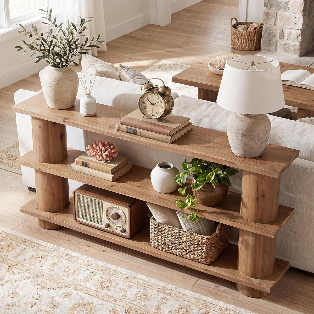 Rear view of the console table showing a lamp, alarm clock, potted plant and woven basket on the shelves.