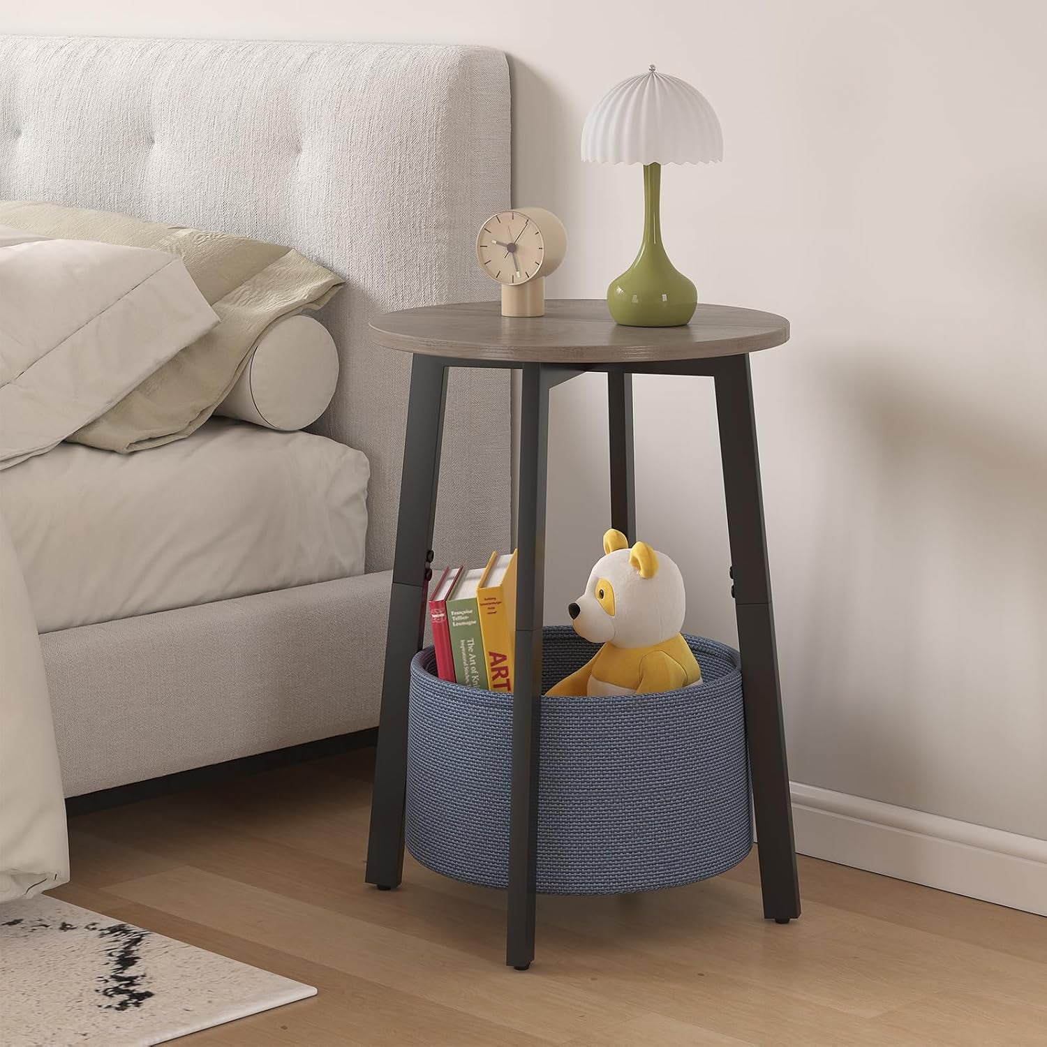 Side table used as nightstand with lamp on top and a blue fabric basket holding books and a toy.