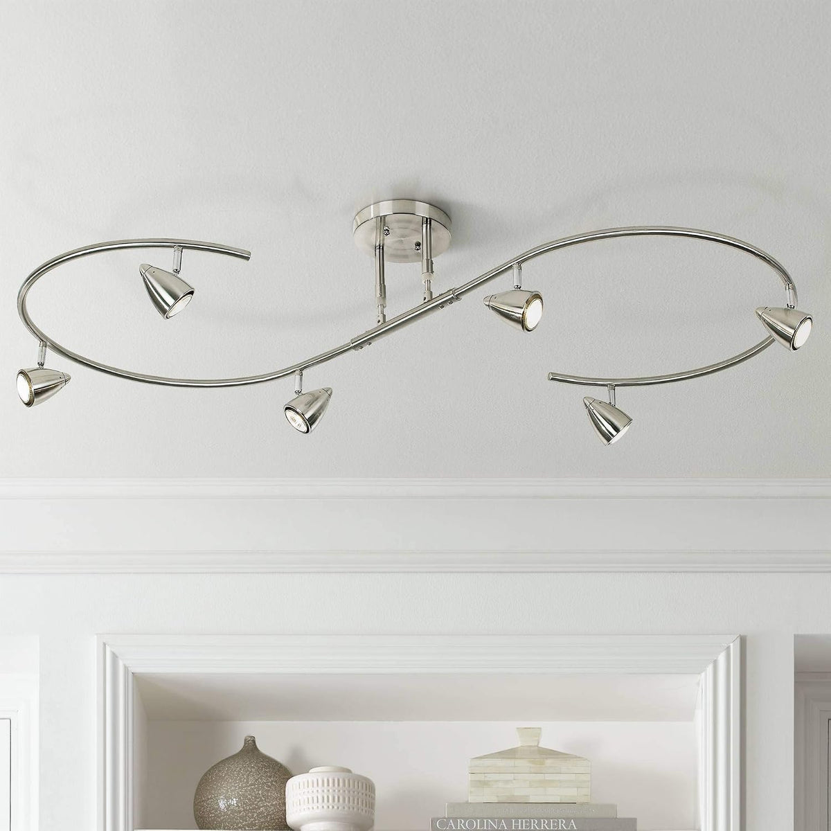 Brushed nickel S-shaped track fixture installed on a white ceiling above a built-in shelf, angled view