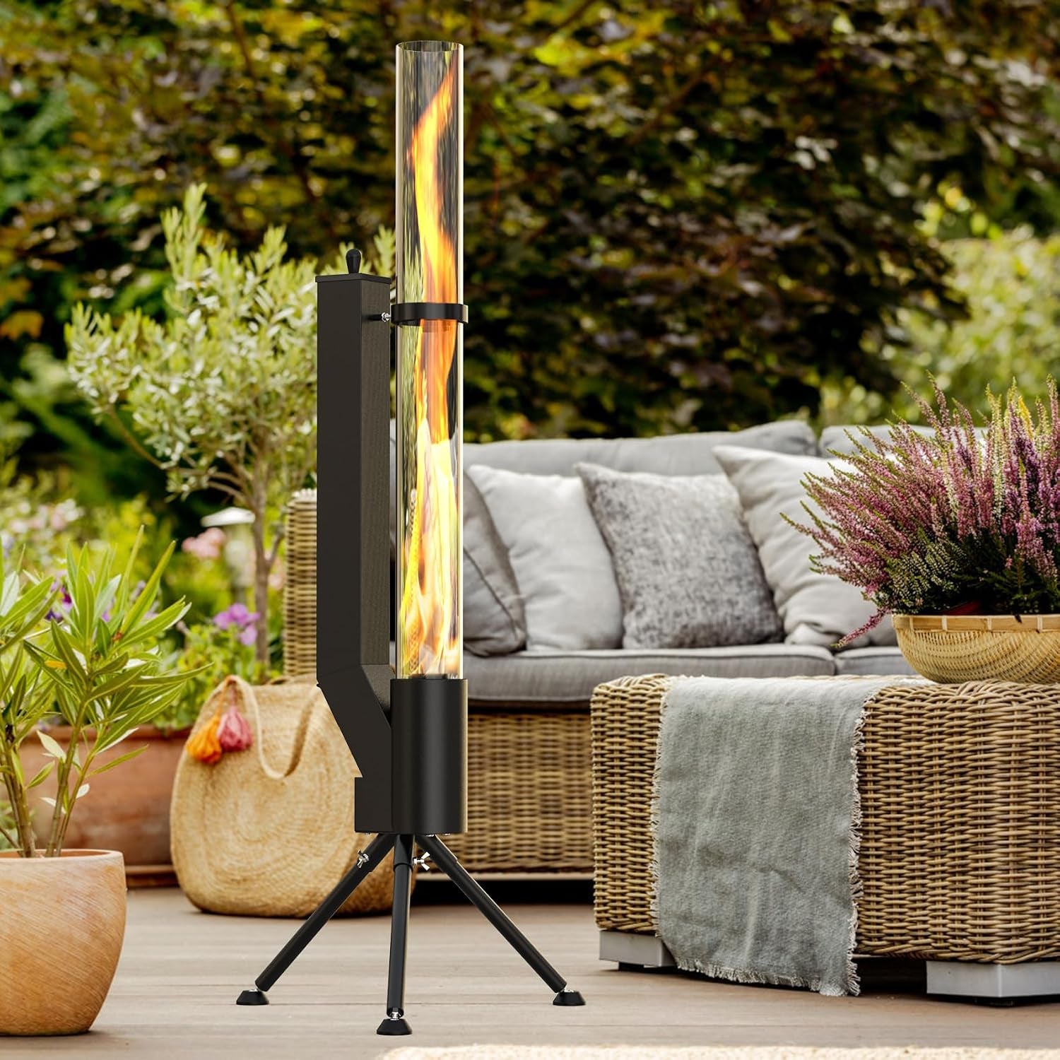 Black wood pellet patio heater beside a wicker outdoor sofa in a garden setting, side view