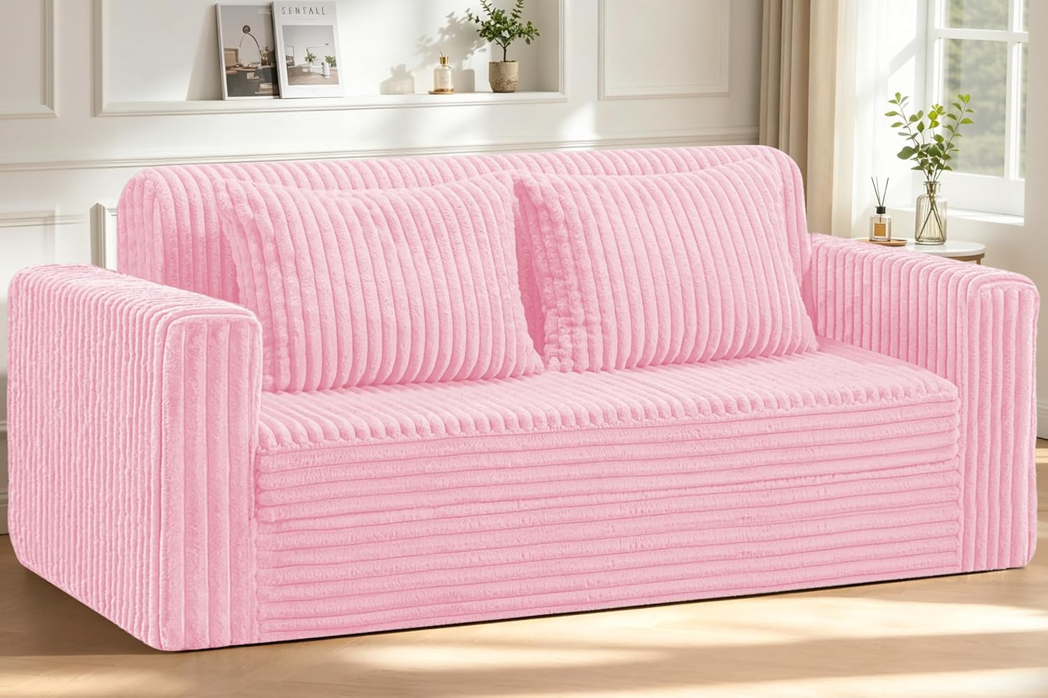 Three-seater ribbed plush sofa in soft pink with two matching back cushions in a sunlit living room.