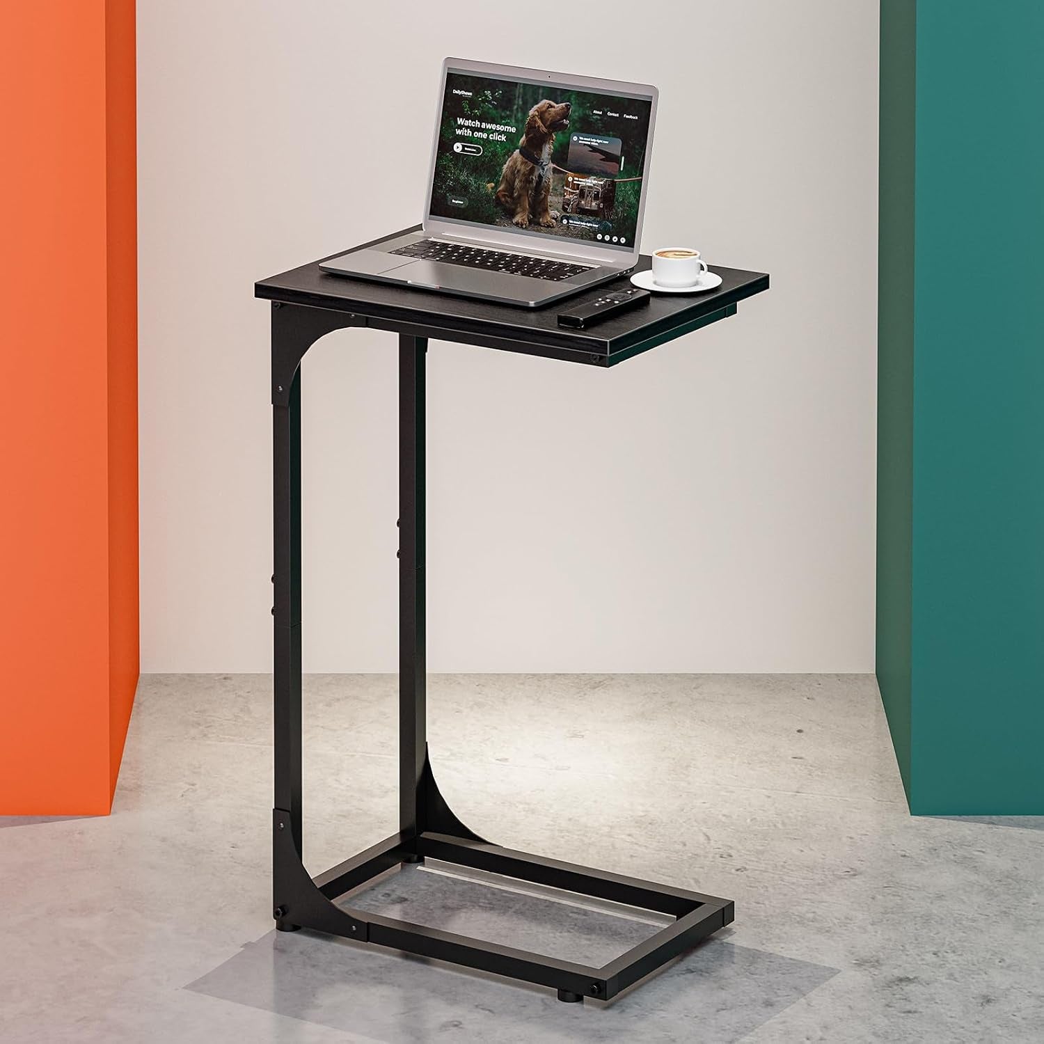 Single C-shaped side table with a black top and black metal frame holding a laptop and cup.