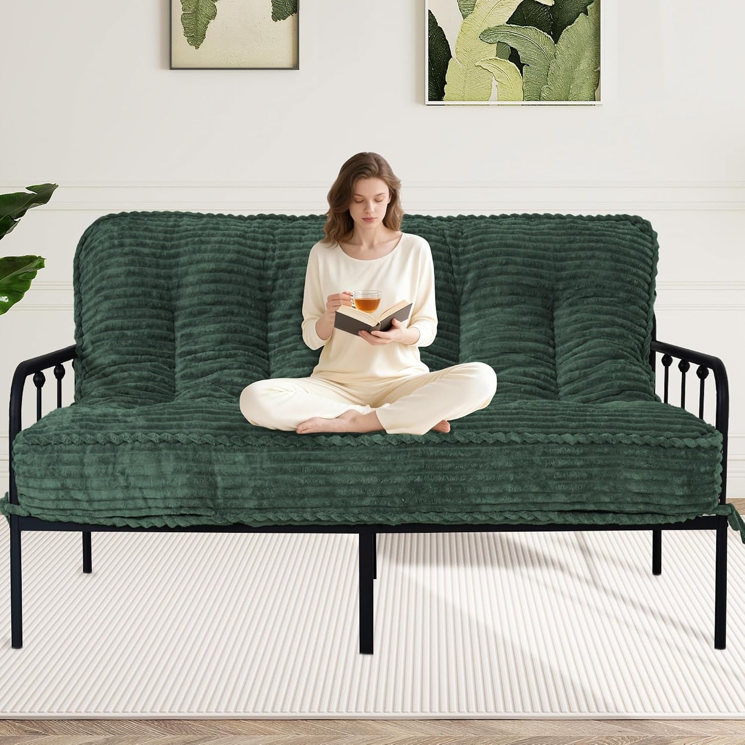 Woman seated cross-legged on a ribbed deep green futon mattress atop a black metal frame