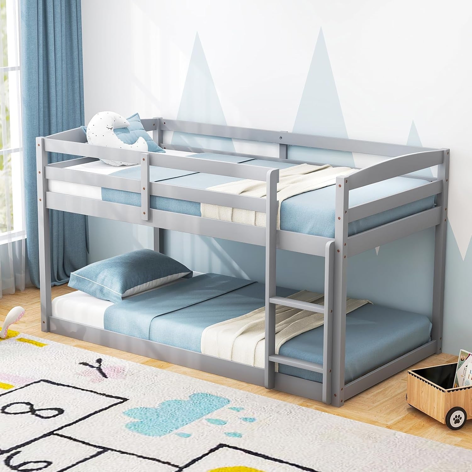Gray twin-over-twin wooden bunk bed with ladder next to a window and blue curtains.