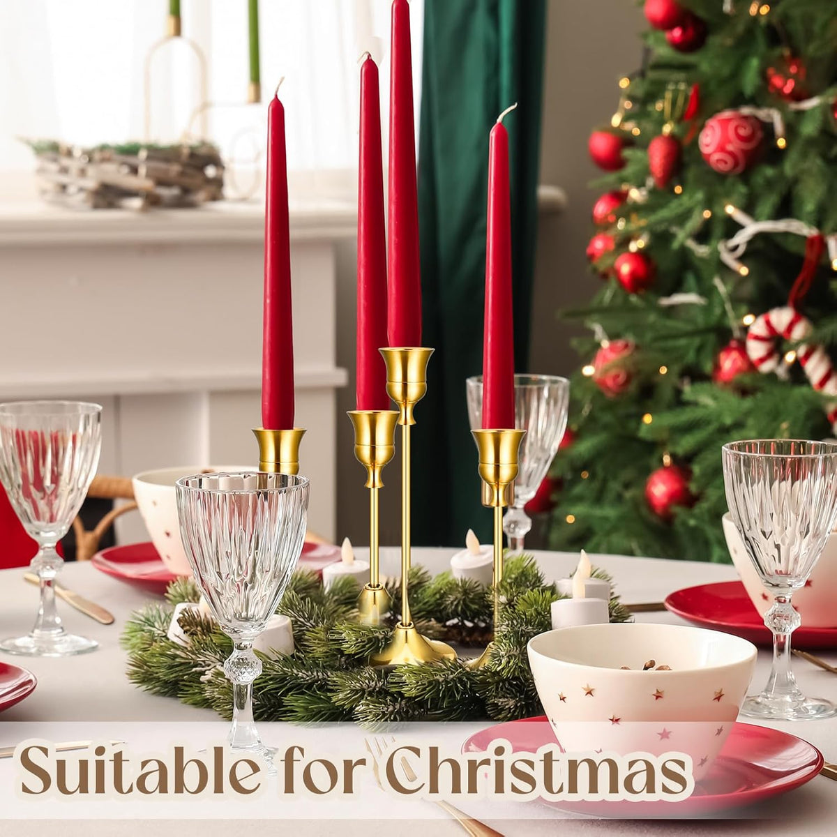 Holiday table scene with red taper candles set in gold holders and a Christmas tree in background
