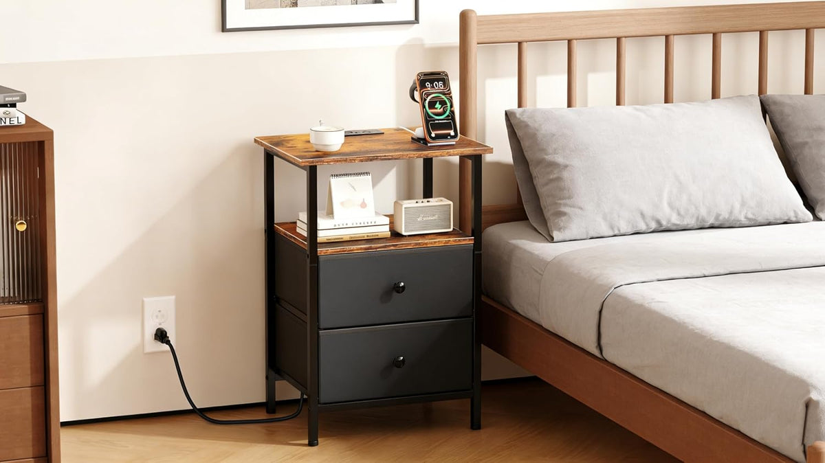 Close crop of the nightstand top shelf showing books, a small speaker, a power cord and the upper drawer front.
