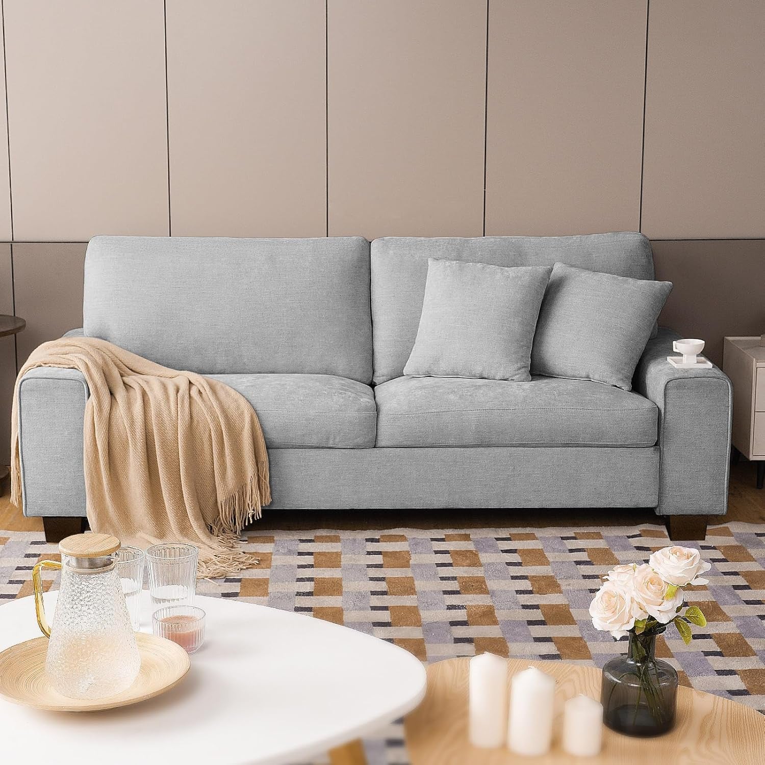 Light gray loveseat centered against paneled wall with throw draped over the arm and decorative tabletop items