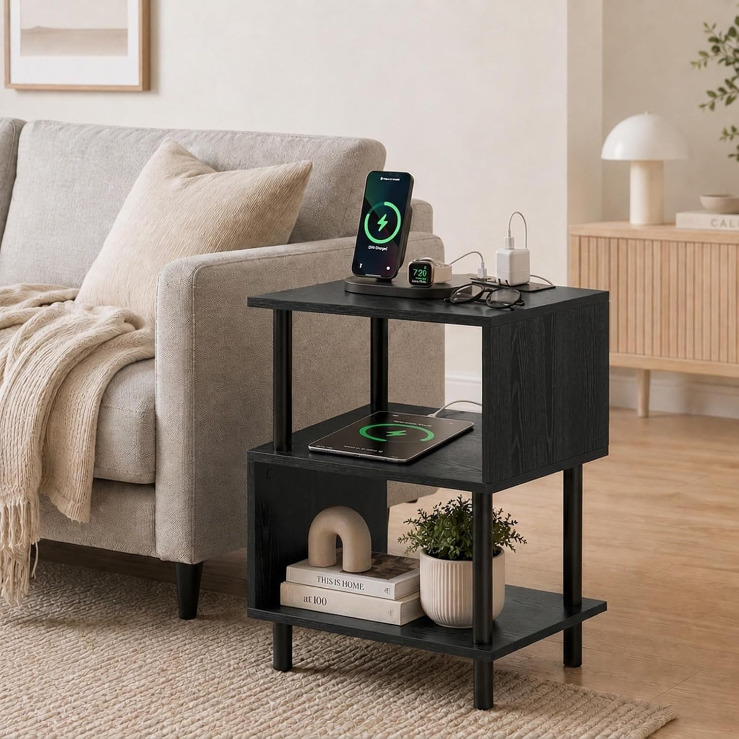 Dark wood three-tier side table next to a beige sofa with phone, glasses and plant on shelves