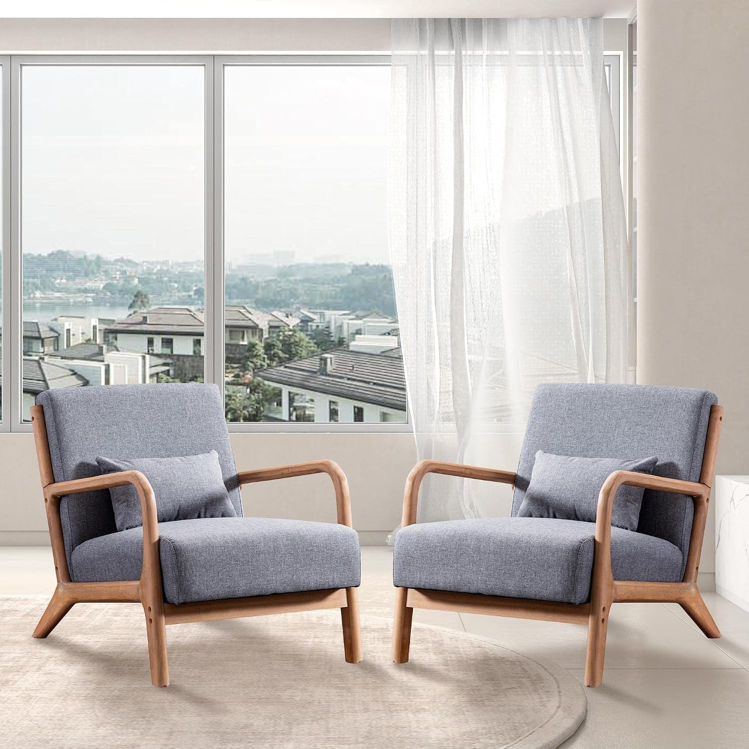 Two mid-century wood frame chairs with light gray cushions placed on a rug by a large window.