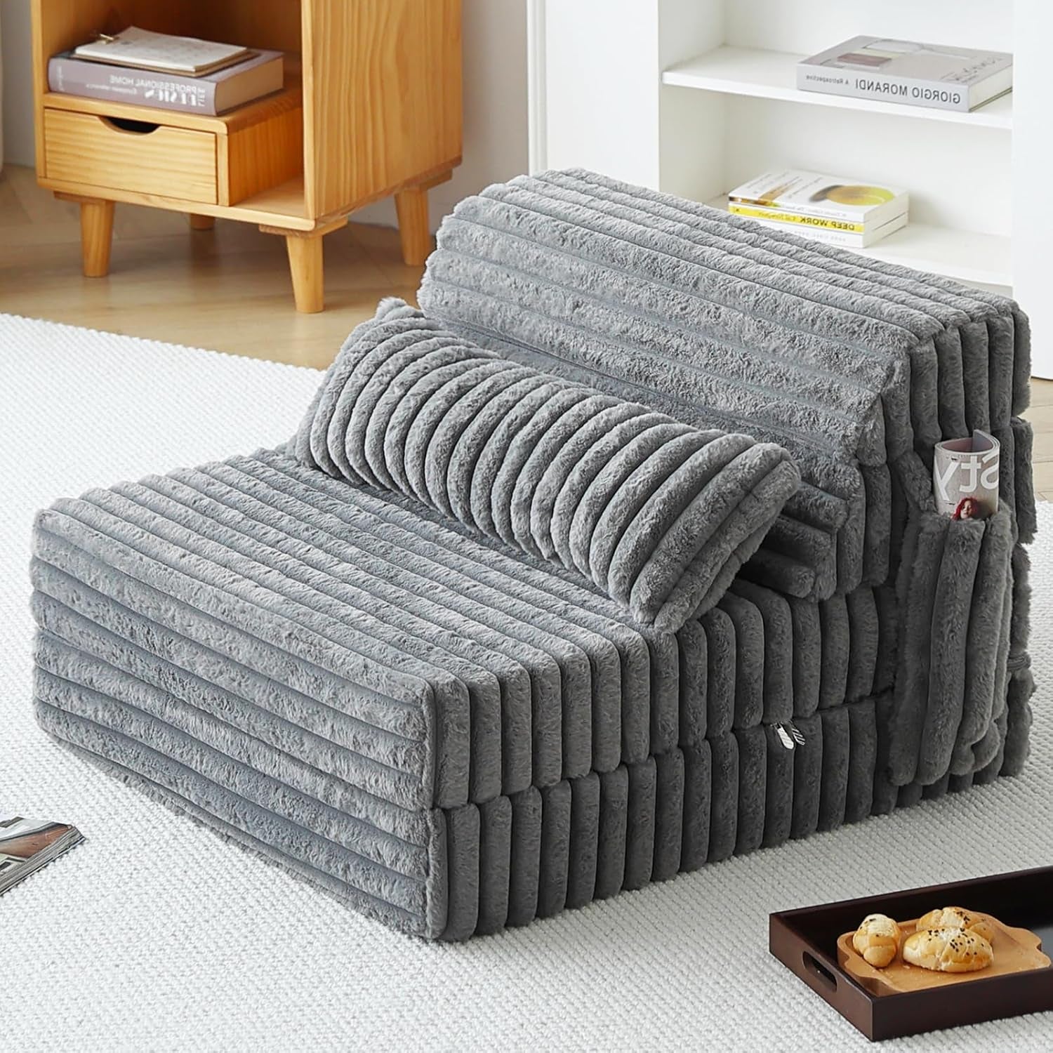 Gray ribbed plush folding sofa mattress with side pocket holding a magazine