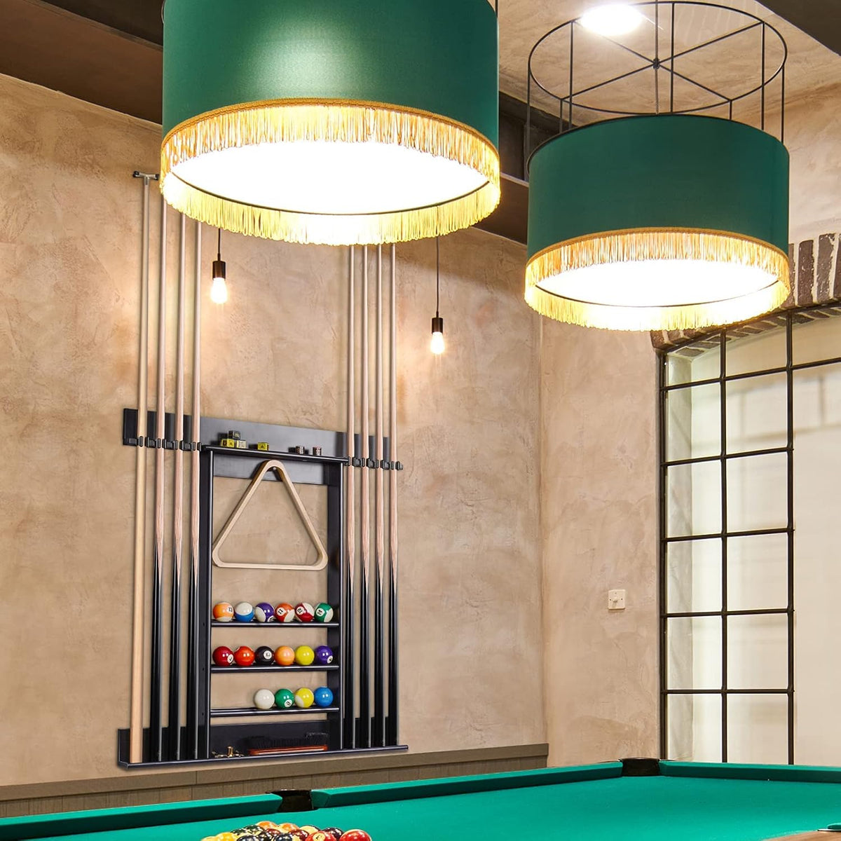 Wall-mounted cue rack holding eight cues and balls above a pool table under two large green pendant lamps.