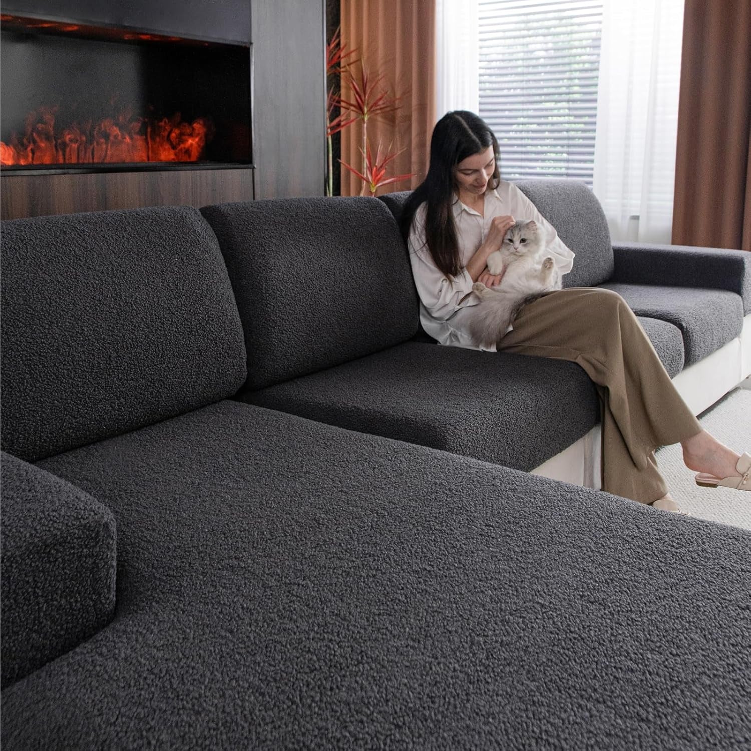 Dark gray textured slipcovers on a sectional with a woman holding a fluffy cat on one seat.