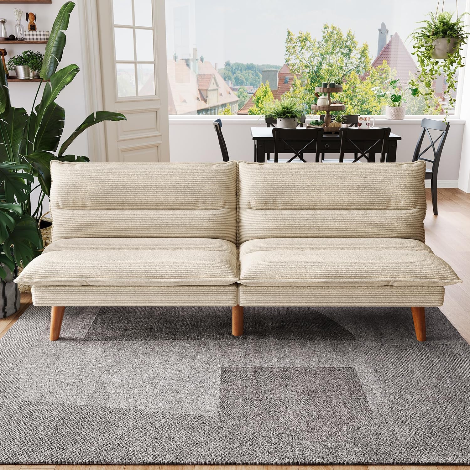 Front view of a beige corduroy futon loveseat set against a dining-room backdrop on a grey rug