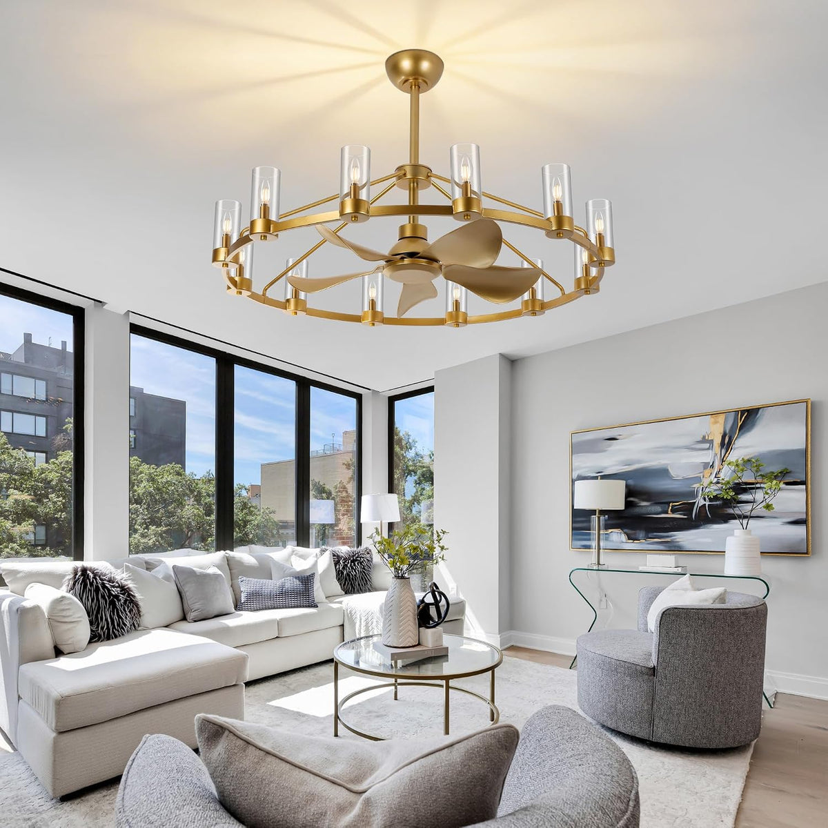 Bright living room with large windows and the gold wagon-wheel chandelier fan centered on the ceiling.