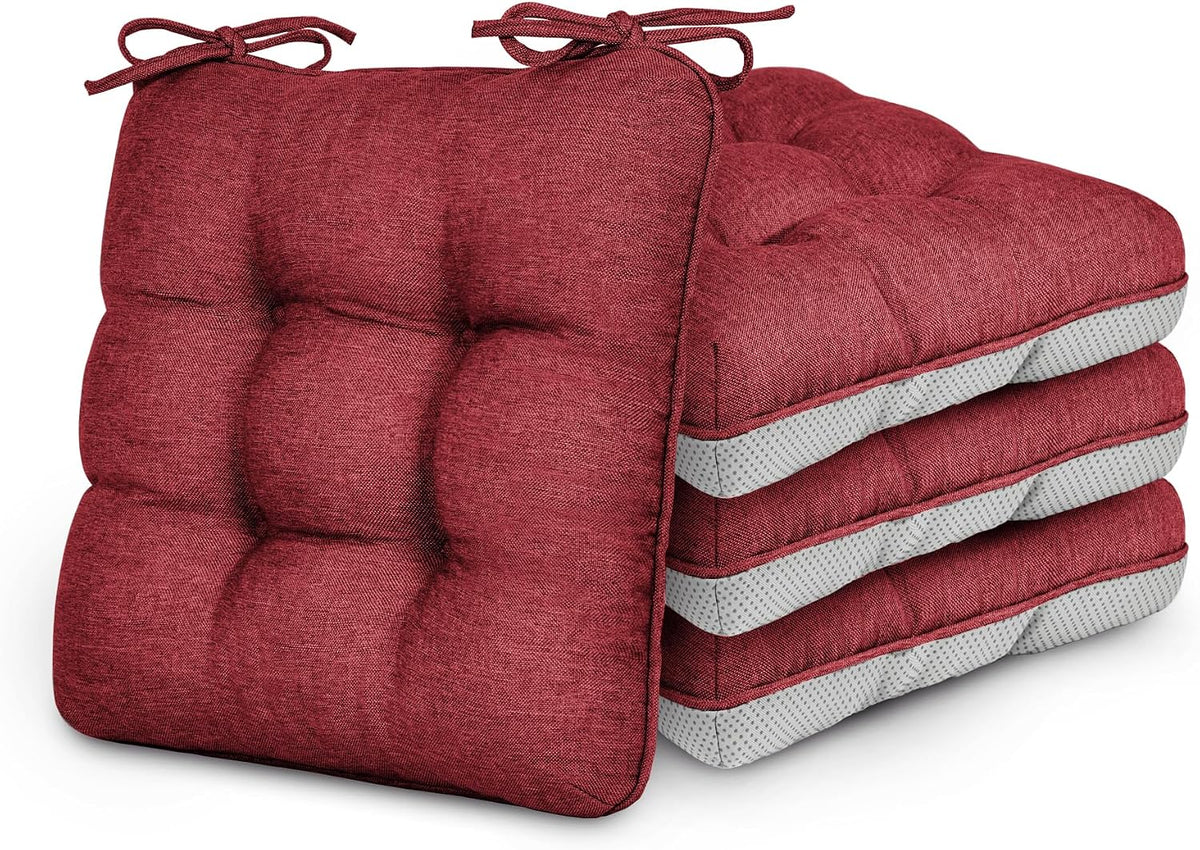 Pile of four tufted red chair cushions with tied corner strings, one cushion leaning forward.