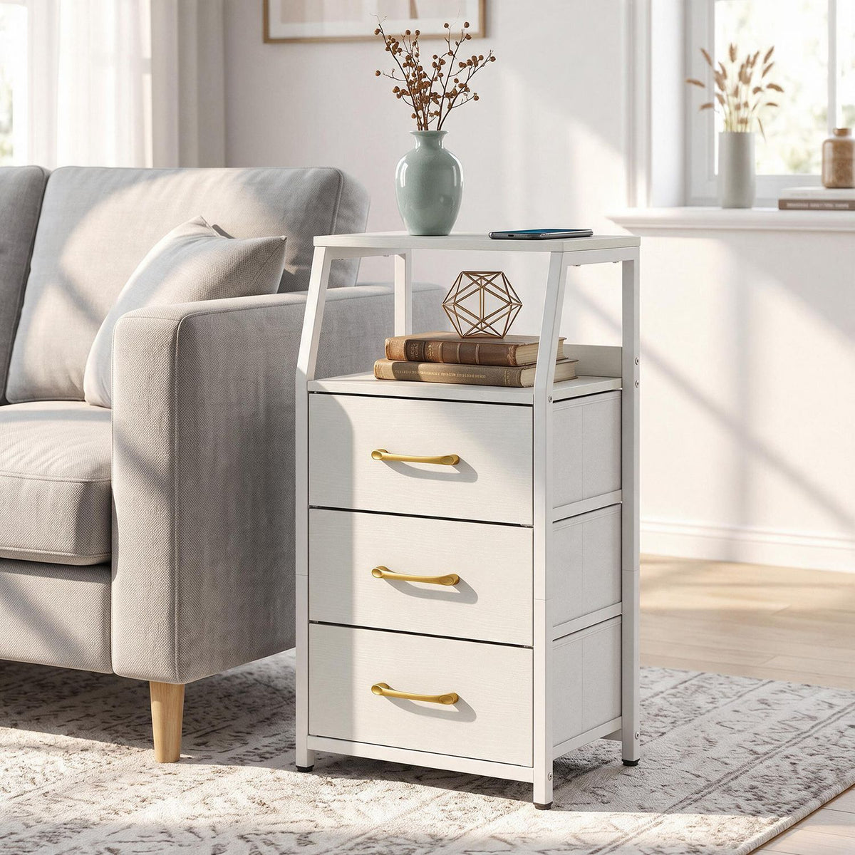 White three-drawer nightstand with open shelves beside a light gray sofa in a sunlit living room.