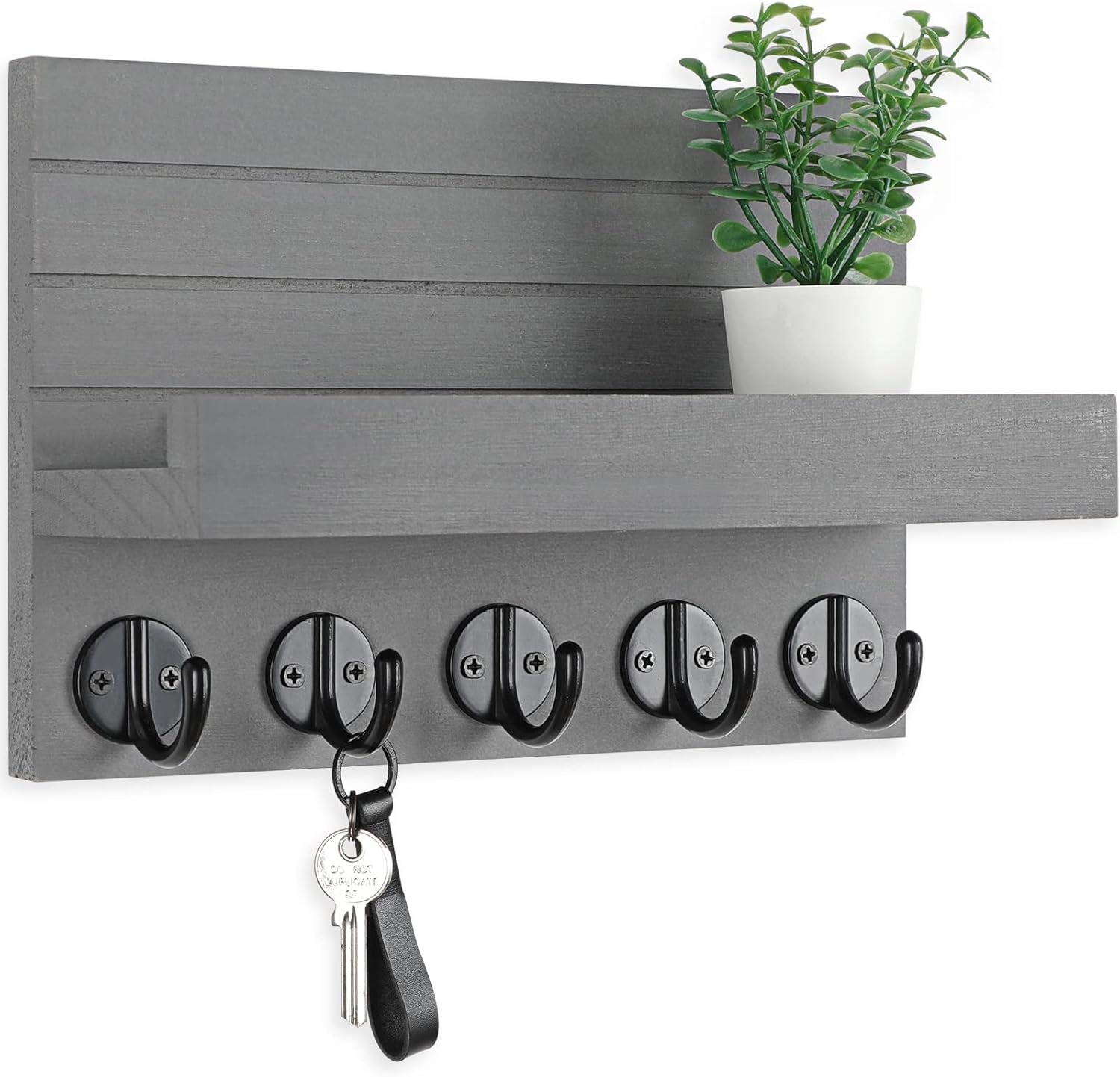 Gray wall key holder with five black hooks, a shelf, potted plant, and hanging key.