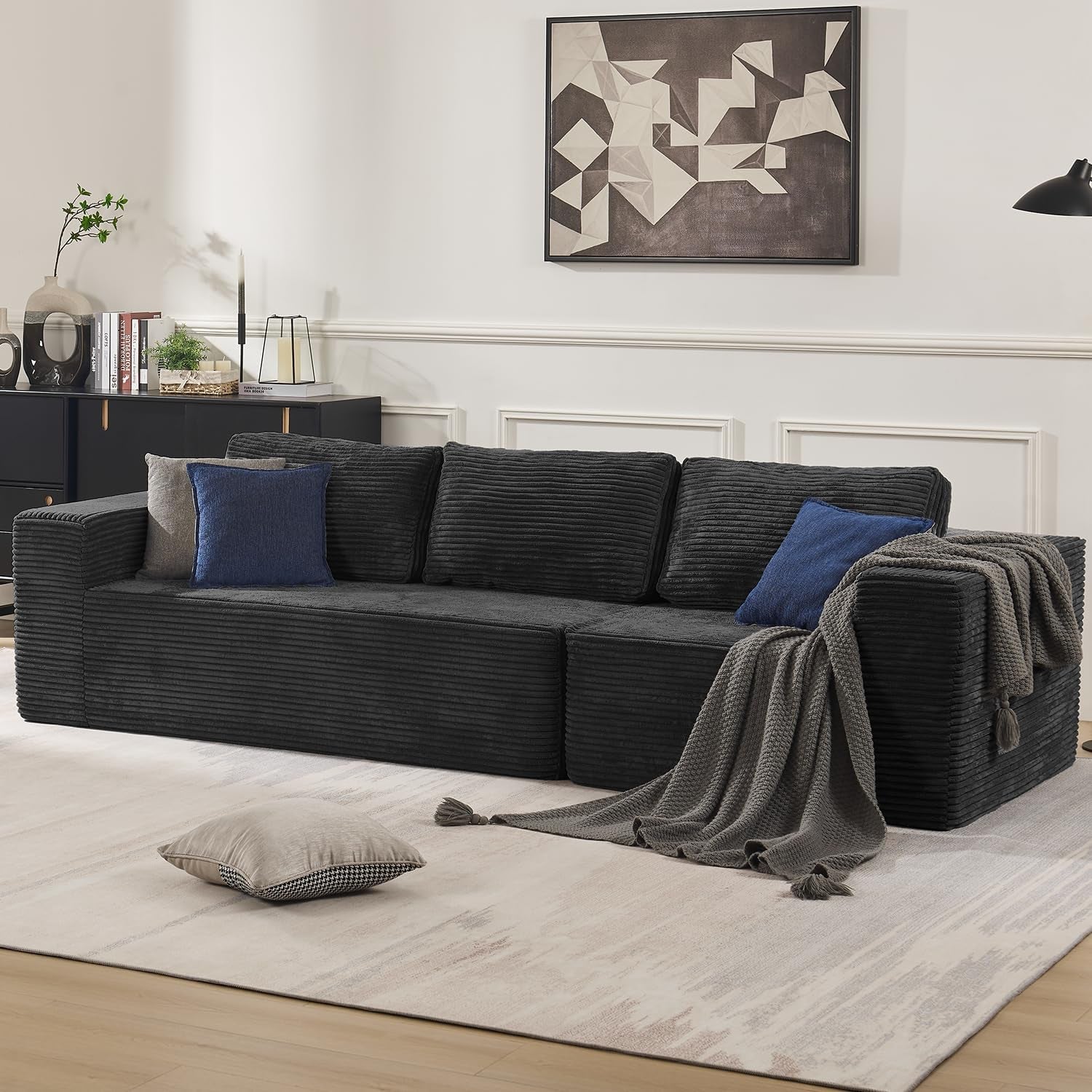 Charcoal corduroy modular sofa with blue and gray pillows and a draped gray throw on the arm