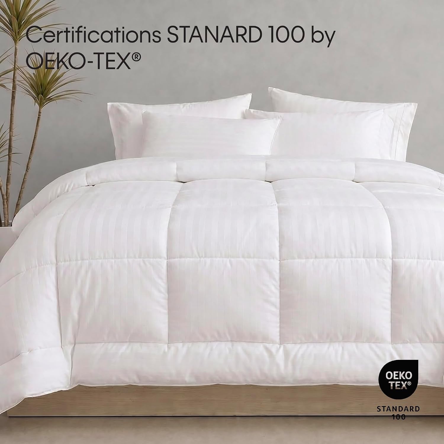 Close front view of a quilted white comforter on a bed with pillows and a plant in the background
