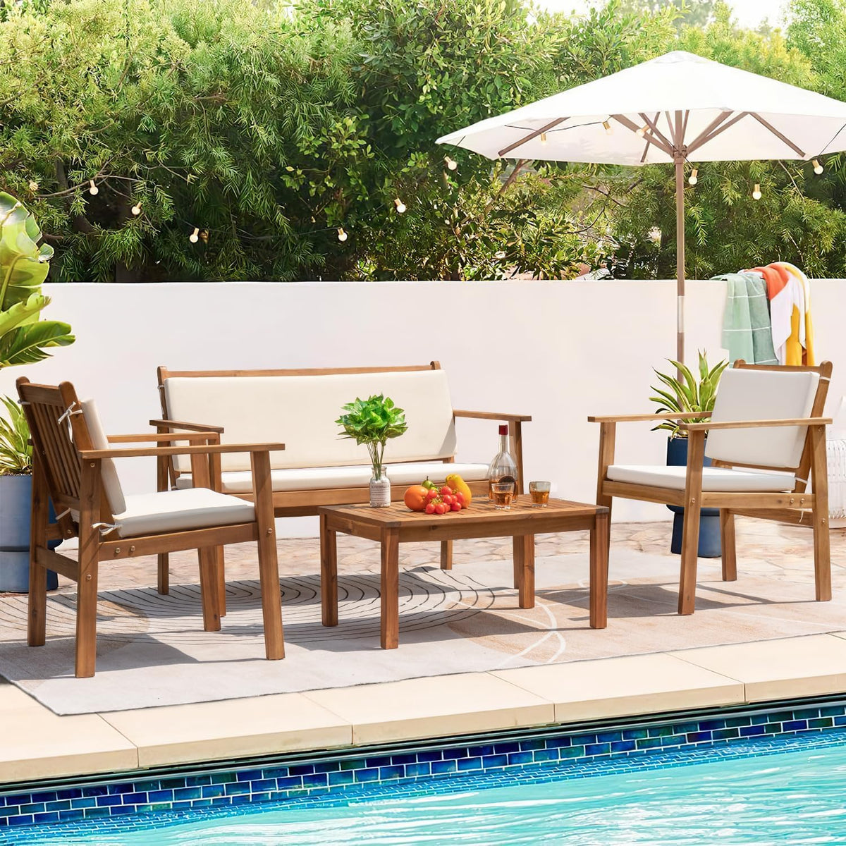 Patio conversation set with loveseat, two chairs and coffee table on an outdoor rug near a pool, side angle