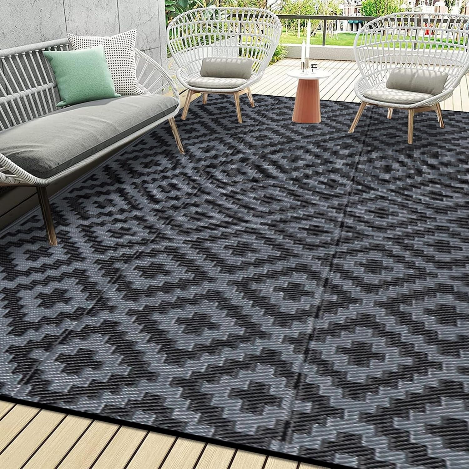 Deck seating area with woven chairs and a charcoal-patterned outdoor rug.
