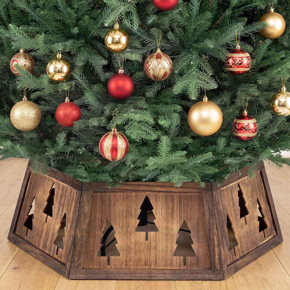 Rustic brown tree collar with tree-shaped cutouts surrounding a decorated Christmas tree.