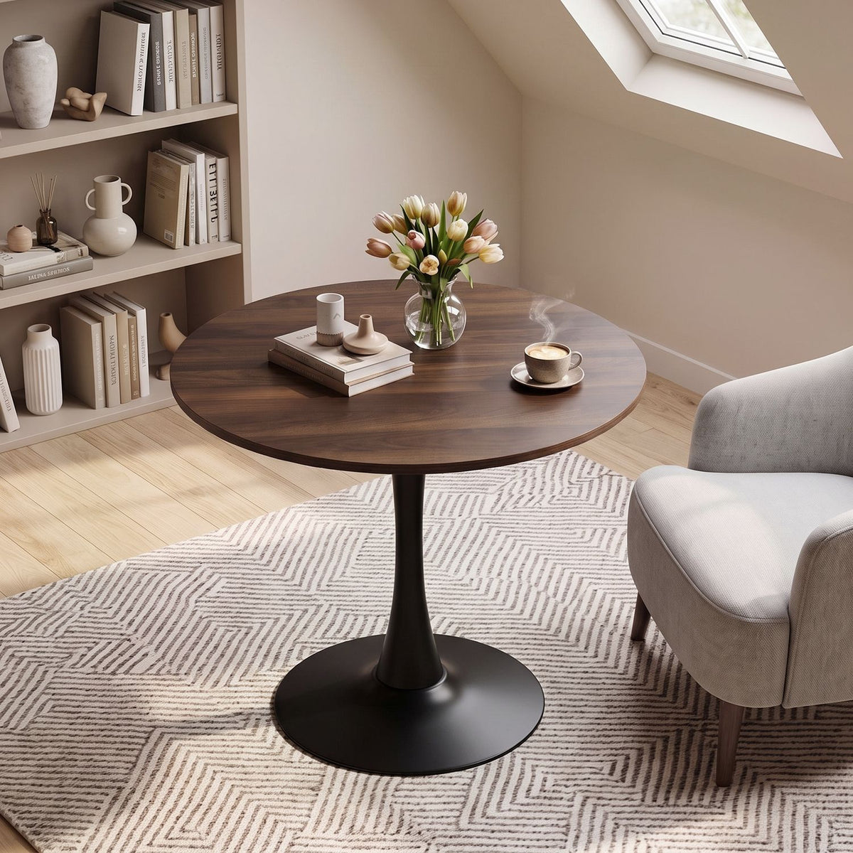 Round dark wood table with a black pedestal base beside a gray armchair in a softly lit room.