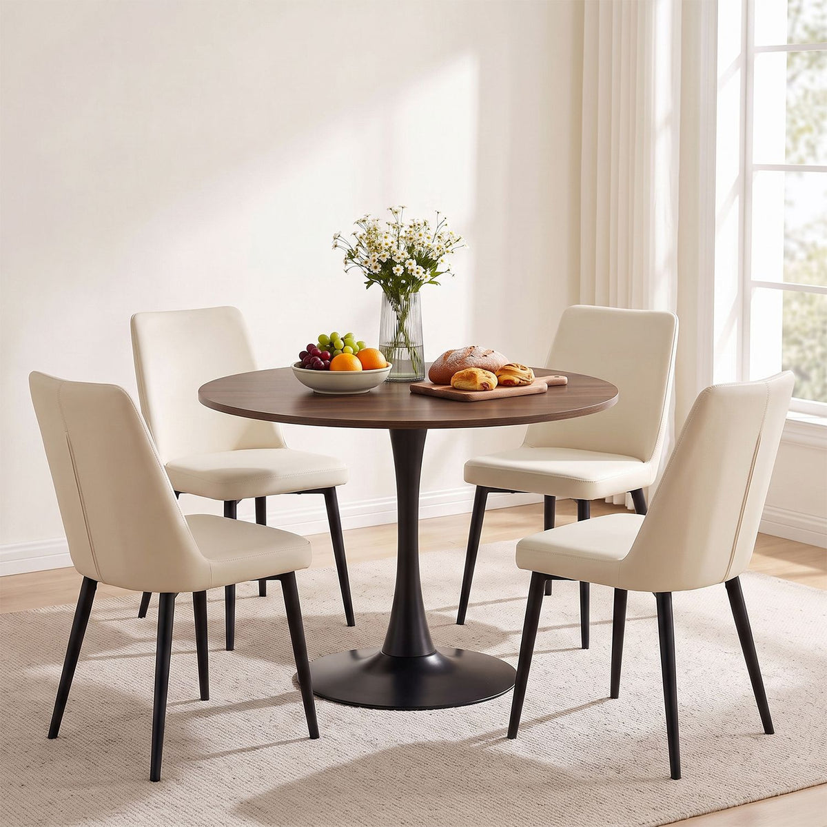 Round dark wood dining table with a black pedestal surrounded by four cream chairs.
