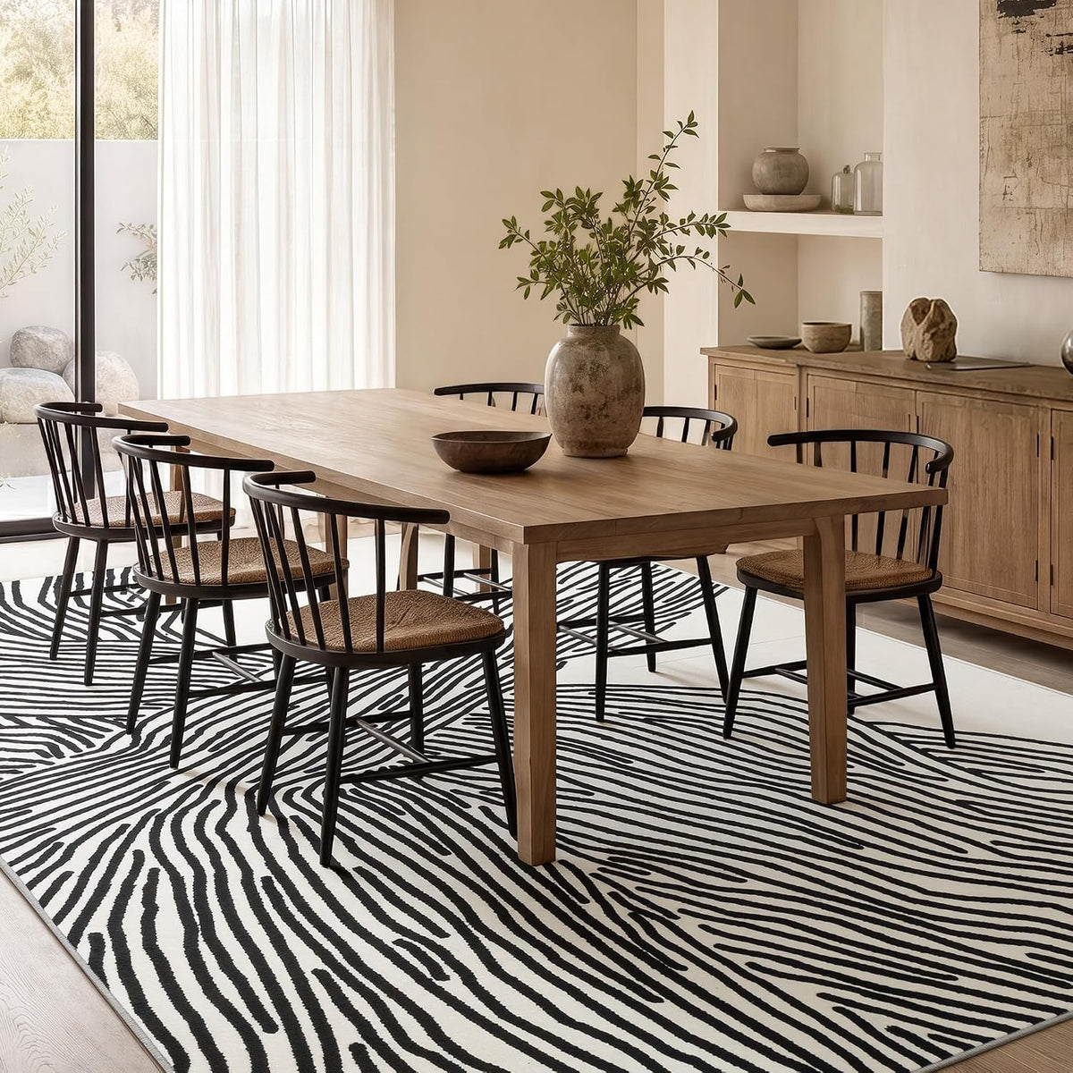Beige and black abstract rug under a wooden dining table with six chairs in a bright dining room setting