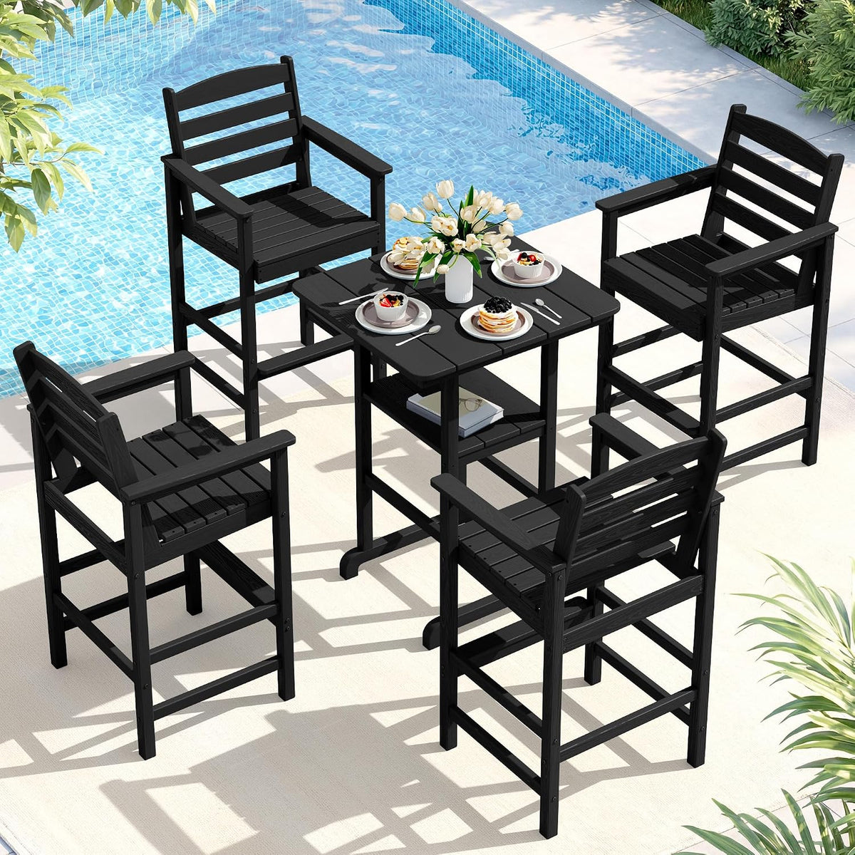 Black bar-height Adirondack chairs and square bar table beside a pool with floral centerpiece and breakfast plates.
