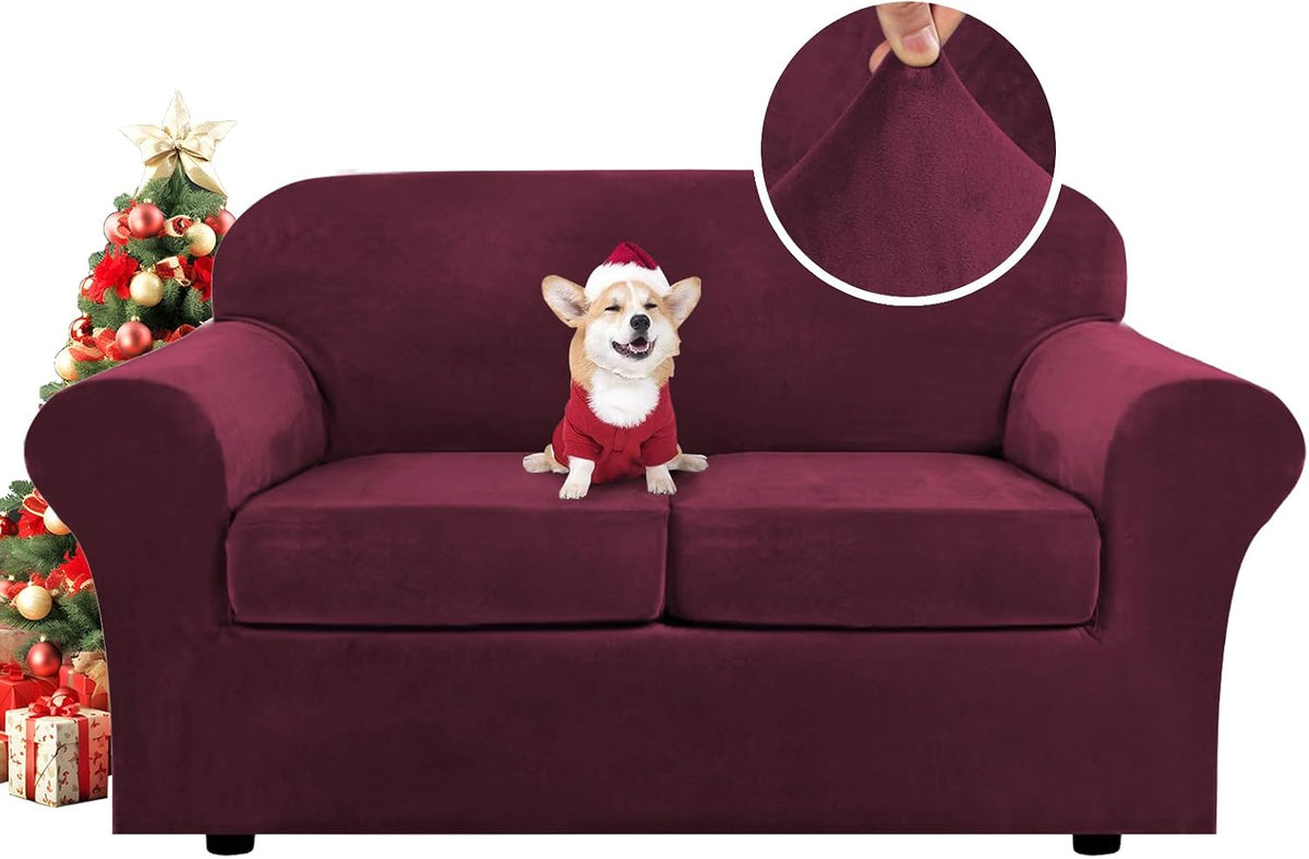 Wine-red two-seat sofa shown front-on with a small corgi wearing a red sweater and a decorated Christmas tree at left.