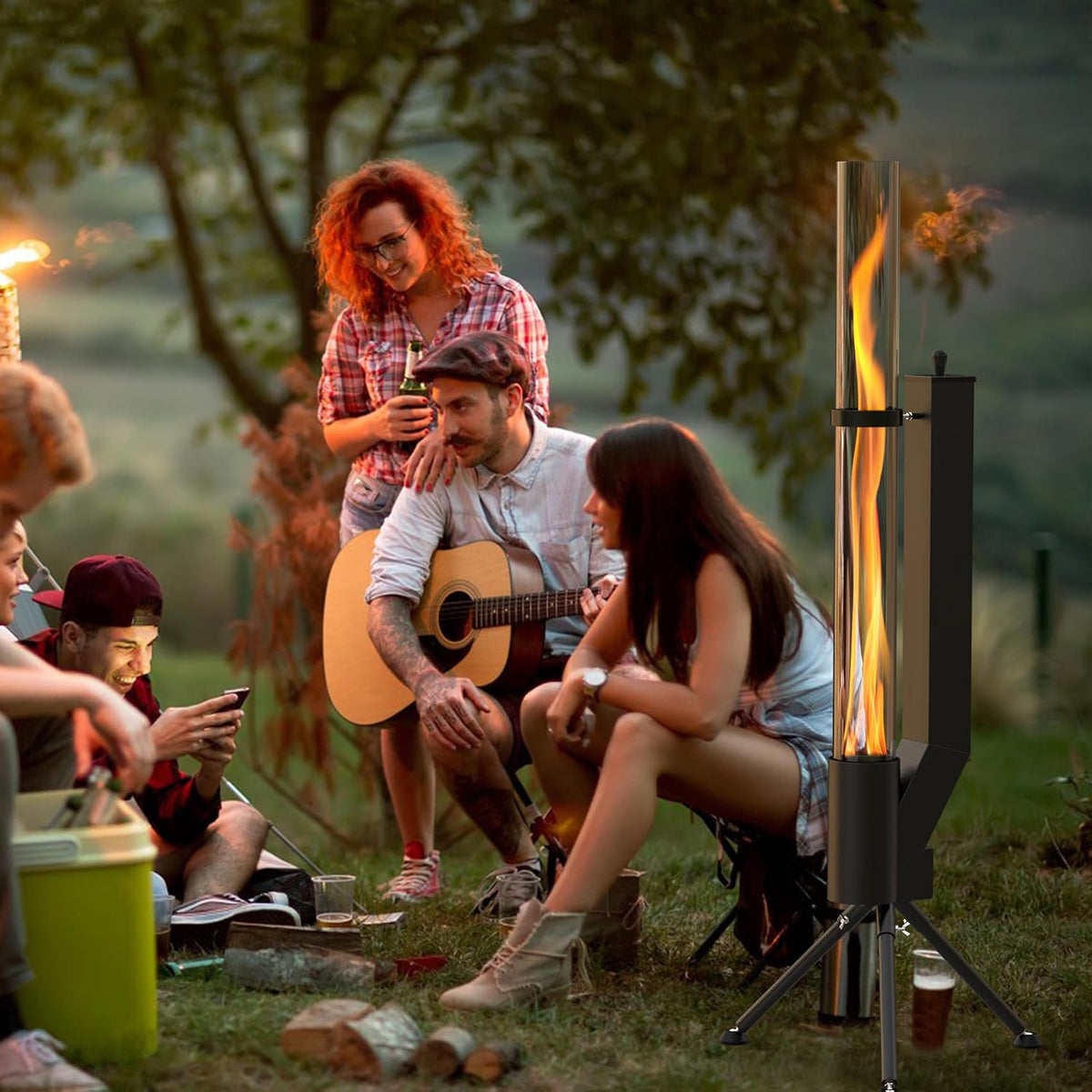 Group of friends gathered outdoors around a glowing vertical pellet heater while one plays guitar at dusk.